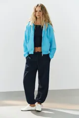 Sudadera con capucha ajustable con cordones, cierre frontal de cremallera, mangas largas, bolsillos tipo canguro y efecto lavado en color celeste.