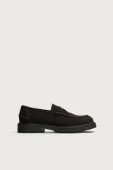 Mocasines de vestir color marrón oscuro, confeccionados en piel con acabado en gamuja serraje. Presentan detalle de antifaz en el empeine con costuras pespunteadas, punta redonda y suela track de goma robusta.