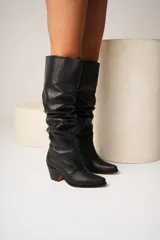 Botas de cuero negro con caña alta arrugada y taco cuadrado.