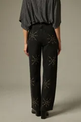 Pantalón de jean negro de corte ancho y tiro alto, decorado con aplicaciones de strass formando estrellas en toda la superficie.