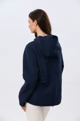 Campera liviana con capucha, de corte clásico, color beige, con bolsillos laterales con solapa y cierre frontal.