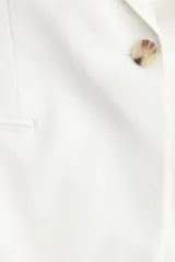 Blazer blanco de sarga con manga corta, botonadura sencilla con un botón, solapas de muesca y bolsillos delanteros ribeteados.