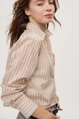 Camisa de manga larga con diseño de rayas verticales en tonos celestes, blancos y marrones, confeccionada en tejido semitransparente con cuello camisero y cierre frontal de botones.