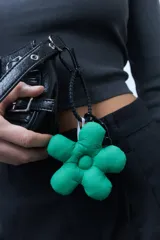 Llavero con forma de flor acolchada de color verde, confeccionado en tela con enganche de goma negro.