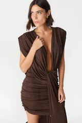 Vestido corto color chocolate, con escote profundo en V y diseño drapeado en la parte frontal y lateral. Presenta hombreras marcadas y una caída fluida que aporta movimiento.