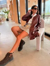 Campera tipo tapado de cuero ovino color bordó, con diseño holgado, cuello redondo y cierre frontal con botones a presión.