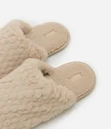 Pantufla cerrada de mujer confeccionada en tejido de poliéster con textura de pelo sintético en color negro, con suela de goma termoplástica.