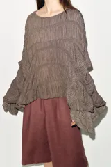 Top de cuello redondo color celeste con textura fruncida, mangas tipo capa y bajo asimétrico.