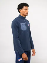 Buzo de micropolar azul con medio cierre frontal, cuello alto y bolsillo con cierre en el pecho. Presenta el logo de Umbro y el escudo del Club Nacional de Football.