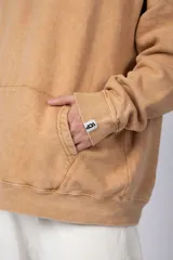 Buzo canguro oversize de algodón friza con efecto de teñido artesanal acid wash en color gris oscuro. Presenta capucha con cordones ajustables, bolsillo frontal tipo canguro y estampa pequeña en el pecho.