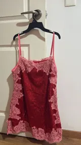 Vestido corto de lentejuelas rojas con detalles de encaje rosado en el escote y el ruedo, de corte recto y tirantes finos.