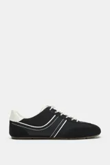 Zapatilla deportiva estilo running color negro, con combinación de materiales, pespuntes decorativos blancos, talón en contraste y cordones claros.