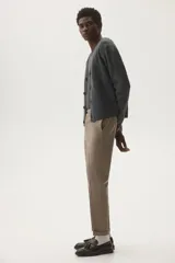 Pantalón de vestir color beige, de corte slim fit, con pinzas marcadas en el frente y dobladillo en el bajo.