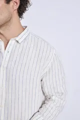 Camisa de corte regular con diseño de rayas verticales finas en tonos claros, cuello clásico y mangas largas con puños abotonados.