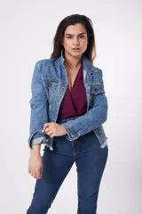 Chaqueta de jean azul con apliques de strass, cuello clásico, cierre frontal con botones metálicos, bolsillos con solapa en el pecho y ruedo desflecado.