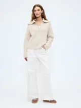 Sweater color beige de tejido de punto con cuello polo y cierre de medio cierre.