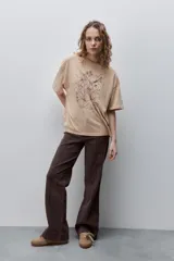 Remera negra de silueta amplia y calce relajado, con cuello redondo, mangas cortas con hombros caídos y estampa botánica en líneas blancas en el frente.