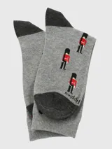 Calcetín de largo medio color gris con estampado de guardias británicos en rojo y negro. Cuenta con talón y puntera reforzados en color gris oscuro.