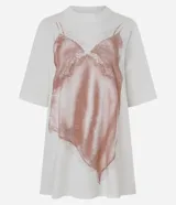 Remera de corte regular confeccionada en algodón, con cuello redondo y mangas cortas. Presenta una estampa frontal de gran tamaño que simula un vestido de lencería con detalles de encaje en tonos rosados.