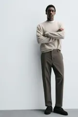 Pantalón de corte slim fit y color negro, confeccionado en tejido elástico. Cuenta con cintura elástica, trabillas, bolsillos frontales y cierre con cremallera y botón.