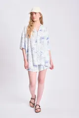 Camisa oversize de manga corta con estampado de palmeras y limones en tonos azules sobre fondo blanco. Confeccionada en lino.