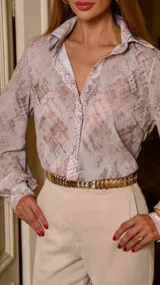 Camisa beige con estampado animal print, de corte clásico, cuello camisero y mangas largas con puños abotonados.