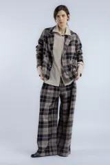 Blazer marrón con estampado a cuadros negros y blancos, de corte recto, solapa clásica, cierre cruzado con botones y bolsillos frontales.