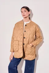 Campera color camel con diseño acolchado, cierre con botones a presión, cuello de piel sintética desmontable, bolsillos delanteros y puños ajustables con lazo.