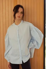Camisa celeste con cuello mao y mangas abullonadas.