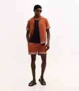 Bermuda masculina de tejido jacquard color terracota, con cintura elástica, cordón de ajuste y detalle de rayas horizontales en el ruedo.
