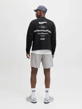 Buzo negro de manga larga con cuello redondo y calce oversize cropped. Presenta un estampado grande en la espalda con texto en blanco que incluye "CORE", "1990", "Functional Aesthetics", "CoreSport©" y tres estrellas.