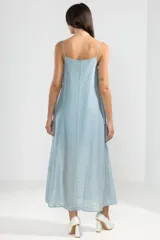 Vestido largo hasta el tobillo color celeste, de tejido arrugado liviano, con escote recto y breteles finos. Presenta lazos en los costados, forro hasta arriba de las rodillas y caída posterior más larga.