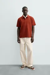 Polo de hombre color terracota con cuello solapa y cierre frontal de botonadura. Presenta un tejido texturizado tipo seersucker y un calce relajado.