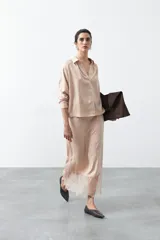 Falda midi de caída fluida color nude/rosa pálido, con cintura elastizada y detalle de encaje en el bajo.