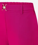Pantalón zanahoria color fucsia de tiro alto, confeccionado en tejido airflow, con cintura elastizada, trabillas y hebillas metálicas.