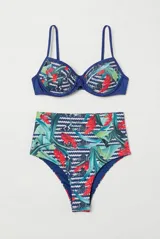 Conjunto de bikini con corpiño de tirantes finos y bombacha de tiro alto, ambos con estampado tropical de hojas verdes y flores rojas sobre fondo azul con patrón geométrico en zigzag.