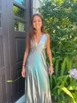 Vestido largo con escote en V, estampado en tonos rojizos y rosados, con un patrón ondulado. Presenta cut-outs laterales bajo el busto y breteles finos que se cruzan en la espalda.