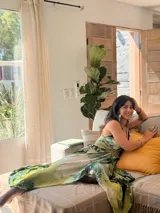 Vestido largo verde con diseño estampado tipo tie-dye y detalles dorados, de corte fluido, un solo hombro y diseño amplio.
