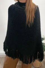 Poncho tejido de lana merino color negro con cuello alto y flecos en el ruedo.