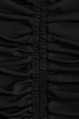 Top de manga larga en punto elástico color negro, con diseño entallado, escote redondo y abertura cut-out en la parte superior con detalle girado. Presenta frunces frontales que crean un efecto drapeado.