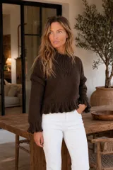 Sweater artesanal de punto en lana merino color marrón, con diseño de volados en hombros, puños y cintura, manga larga y cuello redondo alto.