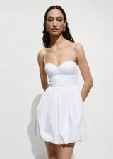 Vestido corto de color blanco con escote corazón y tirantes finos ajustables. Presenta un diseño tipo corset en la parte superior y una falda con volumen tipo globo. Incluye cierre lateral invisible.