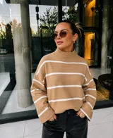 Sweater de tejido de punto en color beige con diseño de rayas horizontales blancas, cuello alto tipo media polera, mangas largas con corte holgado y diseño oversize.