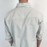 Camisa de manga larga a rayas verticales grises y blancas, con cuello italiano y logo bordado en el pecho.