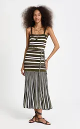 Vestido midi de punto de la marca Le Lis Blanc, con estampado de rayas en tonos verde militar, marrón y blanco. Presenta silueta recta, escote recto, tirantes finos, corpiño ajustado con rayas horizontales, detalle de lazo lateral con cordones trenzados y falda plisada con rayas verticales.