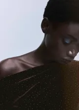 Vestido corto entallado de terciopelo marrón con aplicaciones de brillos, cuello asimétrico de un solo hombro y manga larga.