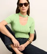 Blusa de tricot color verde claro, de manga corta y escote redondo con abertura frontal.