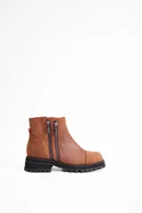 Botin de cuero vacuno color suela, con diseño de caña media, doble cierre lateral y suela track negra de goma.
