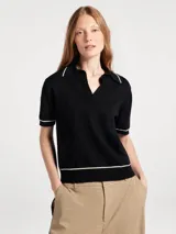 Polo de manga corta confeccionado en tejido de punto, color negro con detalles de líneas en color crema en el cuello, puños y ruedo. Presenta un cuello tipo polo con escote en V.