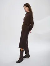 Bota estilo tejana de caña alta, confeccionada en cuero marrón con acabado texturizado. Presenta punta cuadrada, taco bajo y una correa con hebilla metálica ajustable y estribo desmontable en la zona del tobillo.